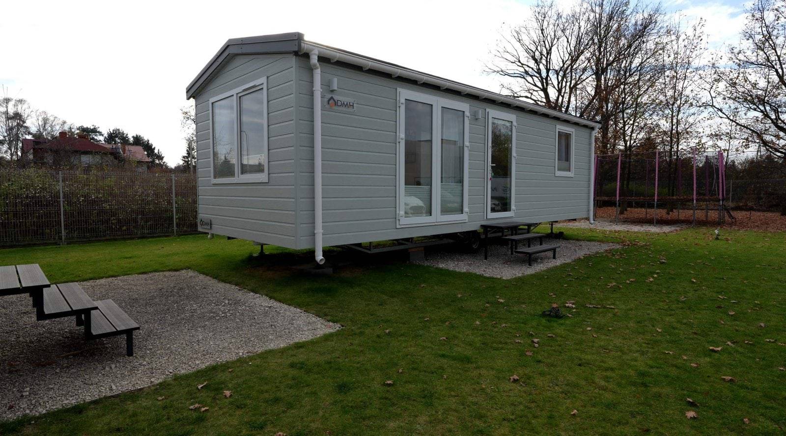 Tatradomy mobile home C — a modern mid-size house with a light façade by a garden pool
